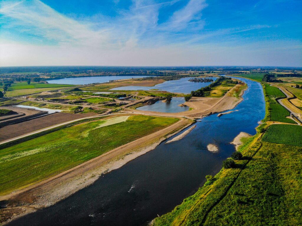 Explore a stunning aerial view of a river winding through agricultural landscapes under a clear blue sky.